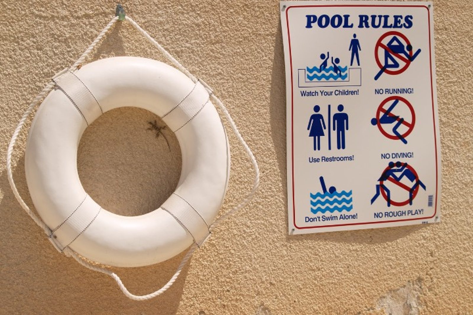 Safety signage and rescue float displayed at a pool area