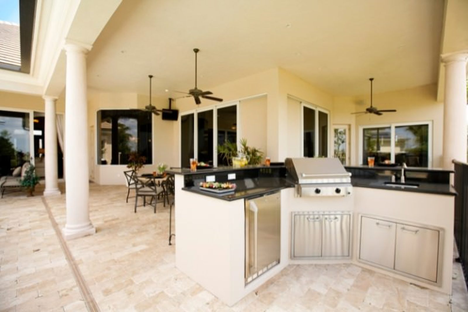 Spacious outdoor kitchen featuring soft neutral finishes, dark countertops, and built in grill and storage