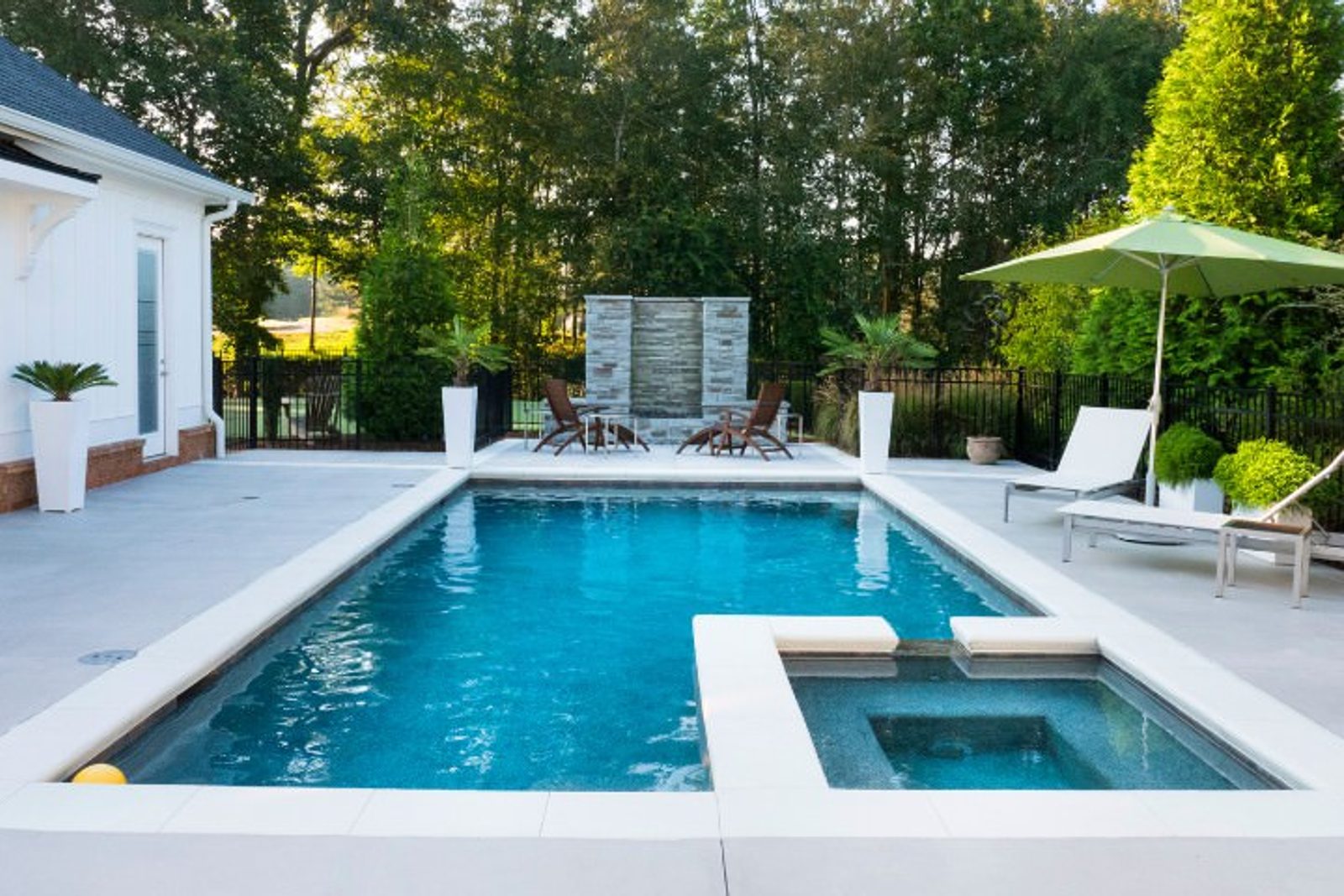 Modern attached spa design in a backyard pool