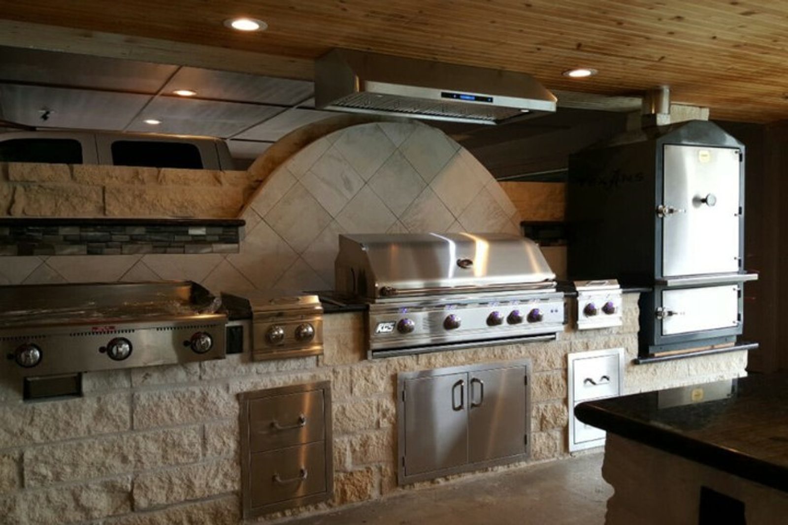 Covered outdoor kitchen featuring stainless steel appliances and stone countertops