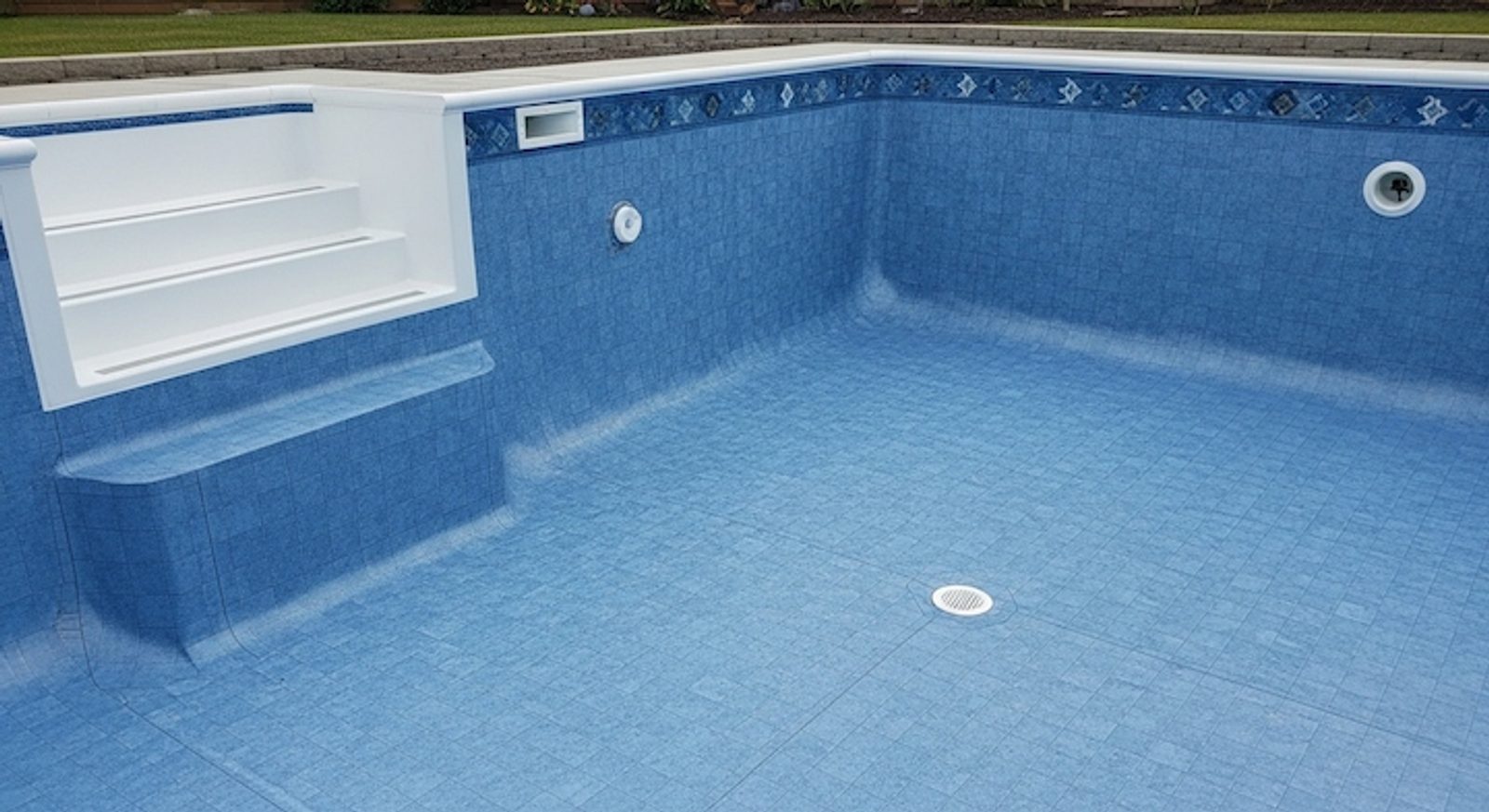 Empty vinyl liner pool showing blue printed pattern, molded steps, and skimmer opening