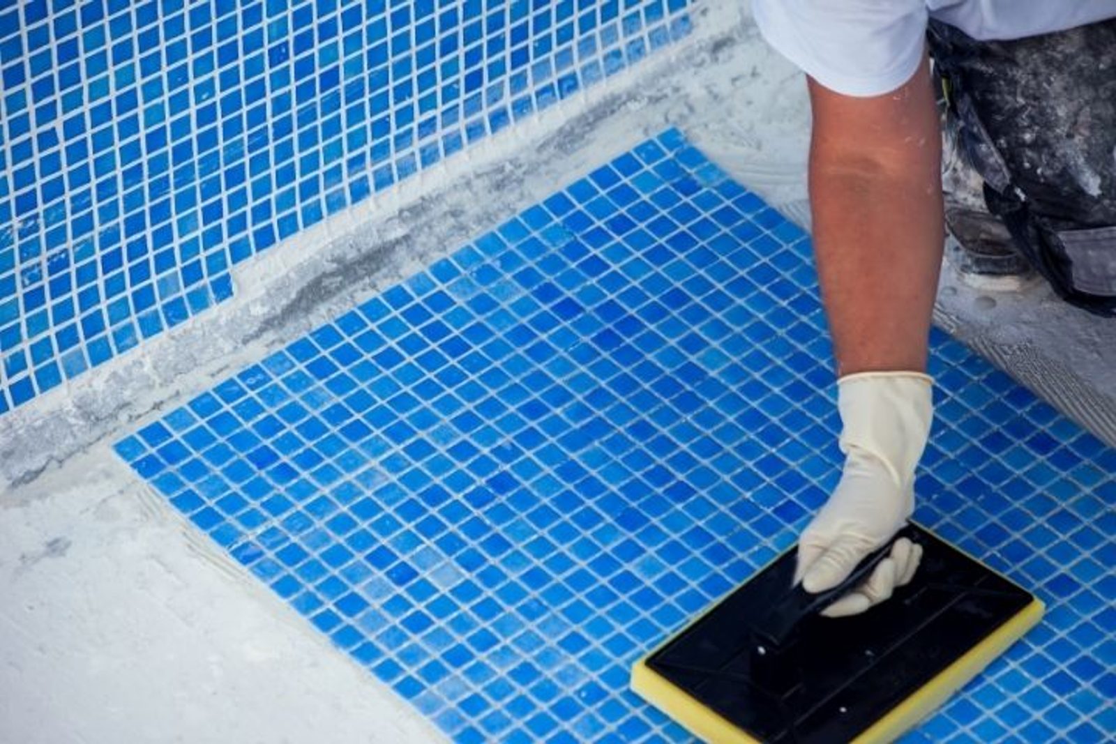 Houston pool builder installing small blue pool tiles during a residential pool renovation