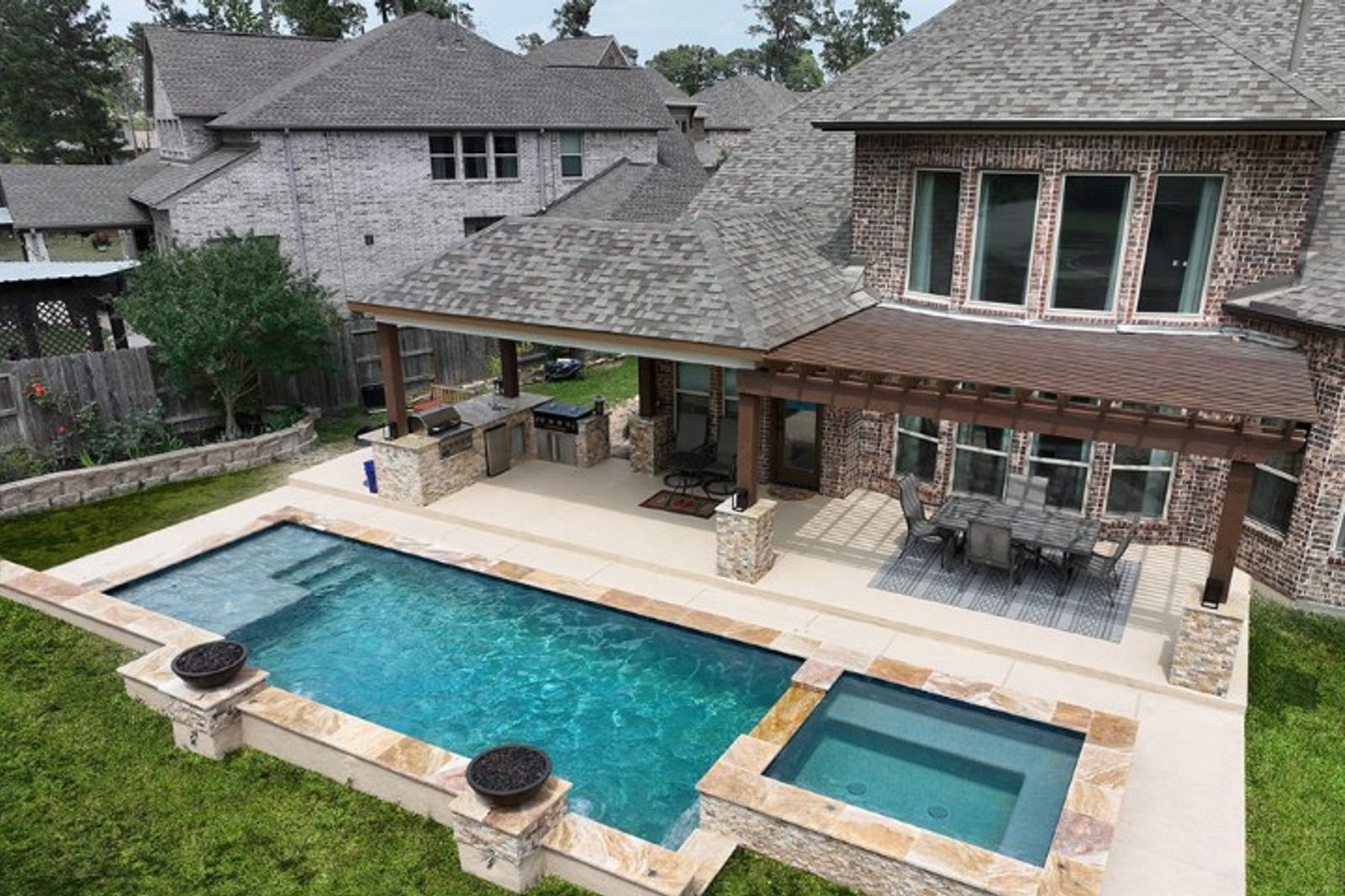 Functional outdoor living space with a shaded kitchen, pool, and organized dining layout
