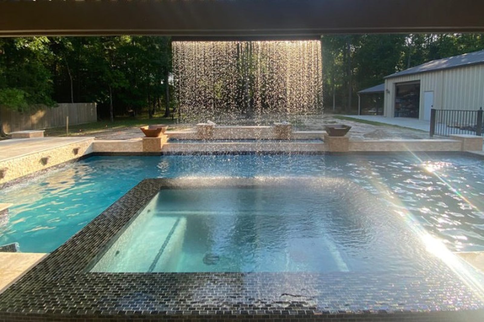 Elevated spa with a rain curtain feature flowing into a timeless pool, symmetrical layout