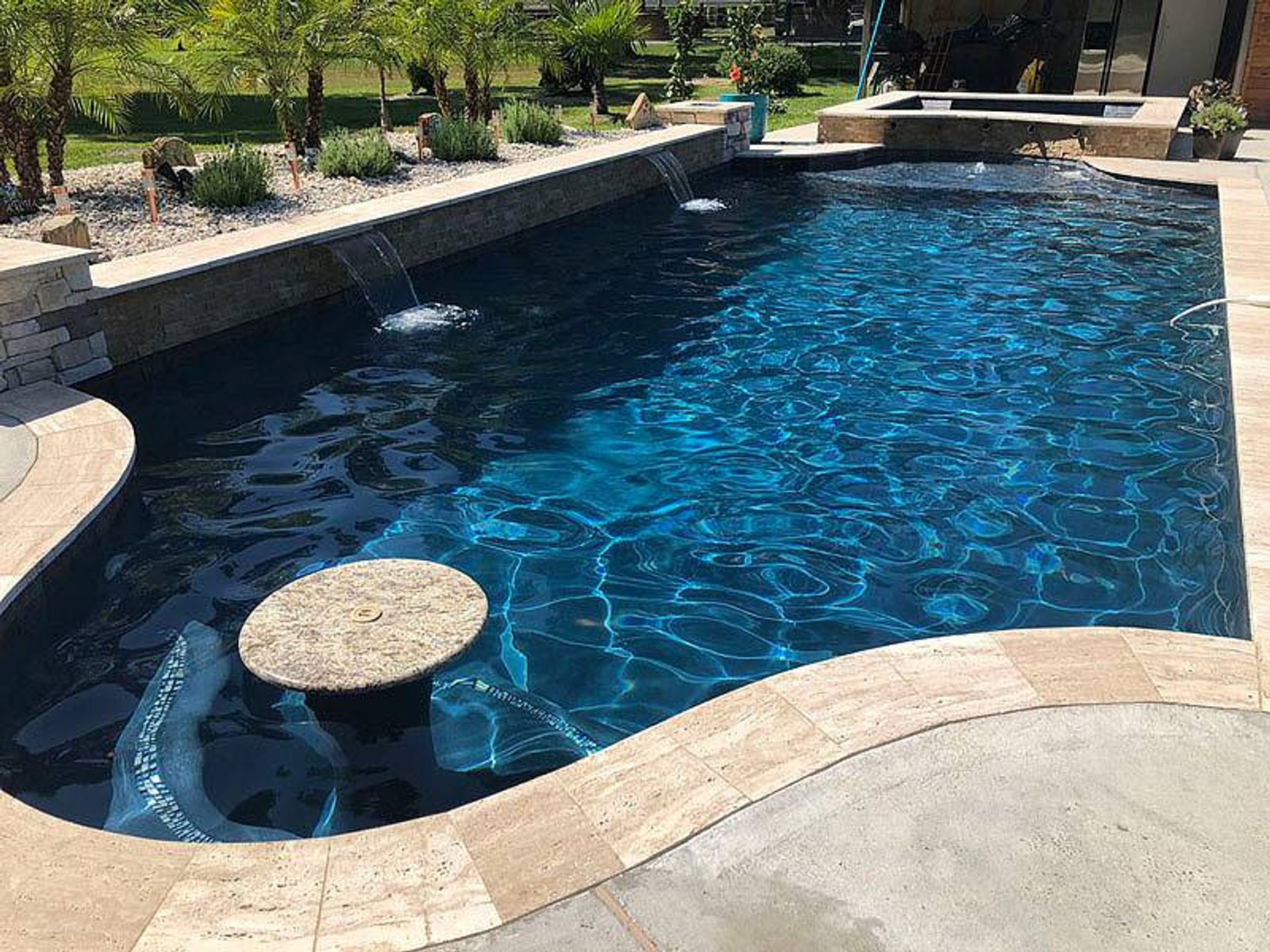 Custom-designed pool and spa featuring built-in underwater bar seating and waterfall features