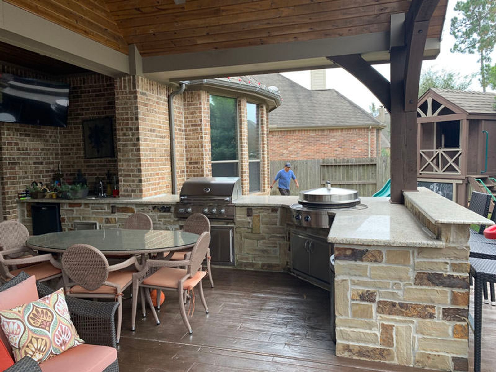 Houston outdoor kitchen with stone countertops, stainless steel appliances, and a covered dining area