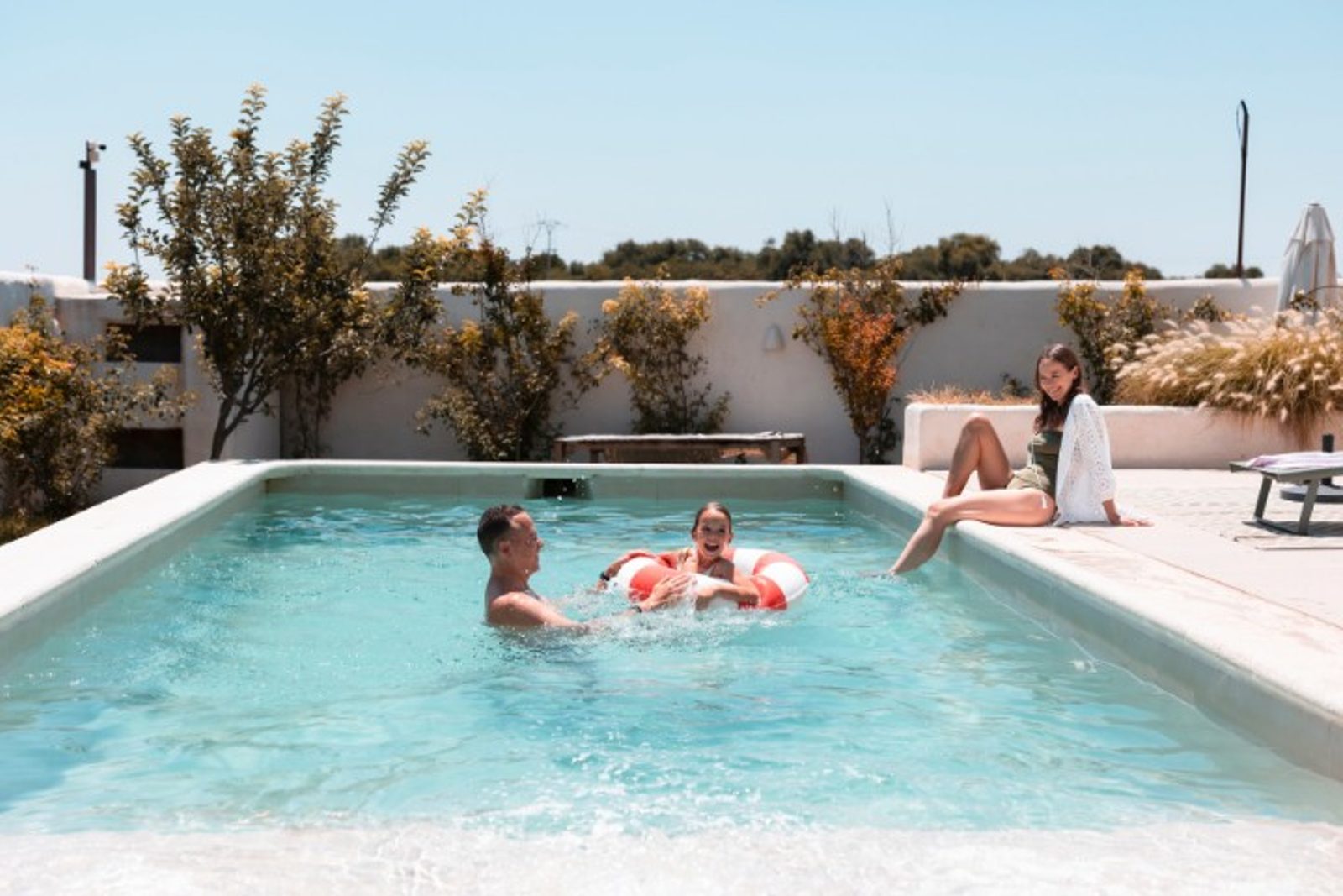 Family enjoying a backyard pool with layout showing space needs for different inground pool types