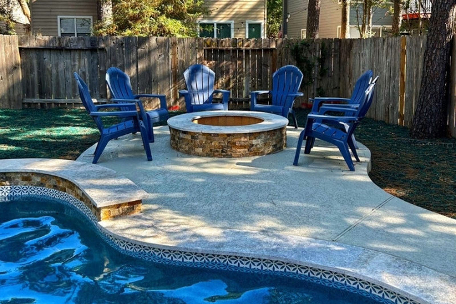 Poolside fire pit area with Adirondack chairs in a Houston outdoor living space