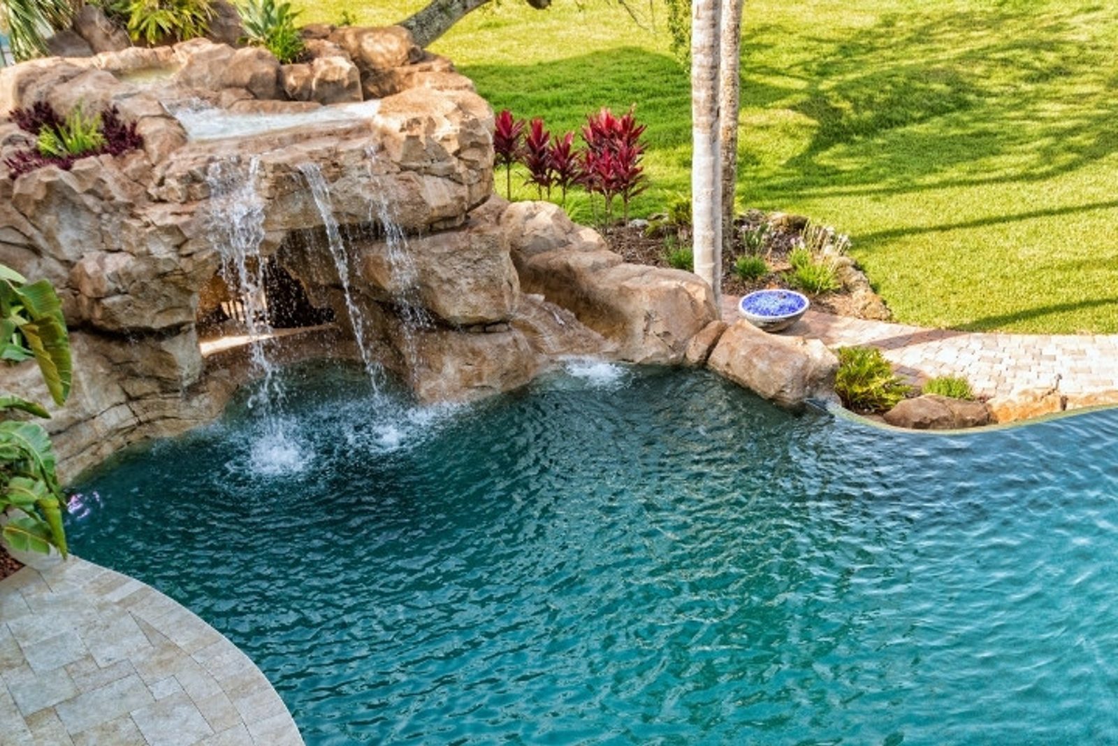 Luxury pool with natural rock waterfall and landscaped backyard in Texas