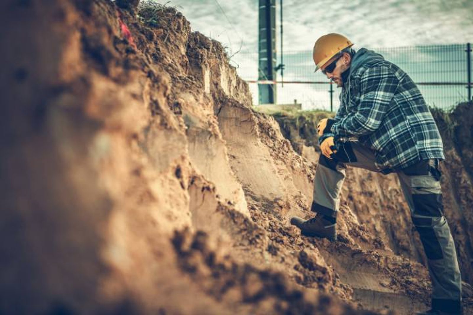 Pool builder inspecting soil stability during early stage of pool construction