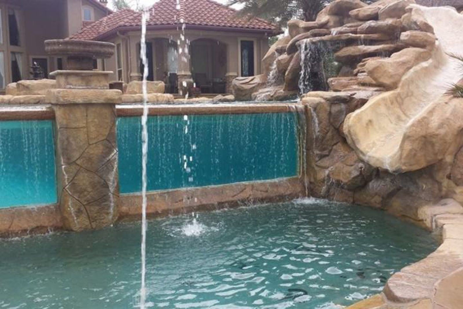 Backyard pool with a cascading spillway, creating a stunning waterfall effect between multi-tiered levels