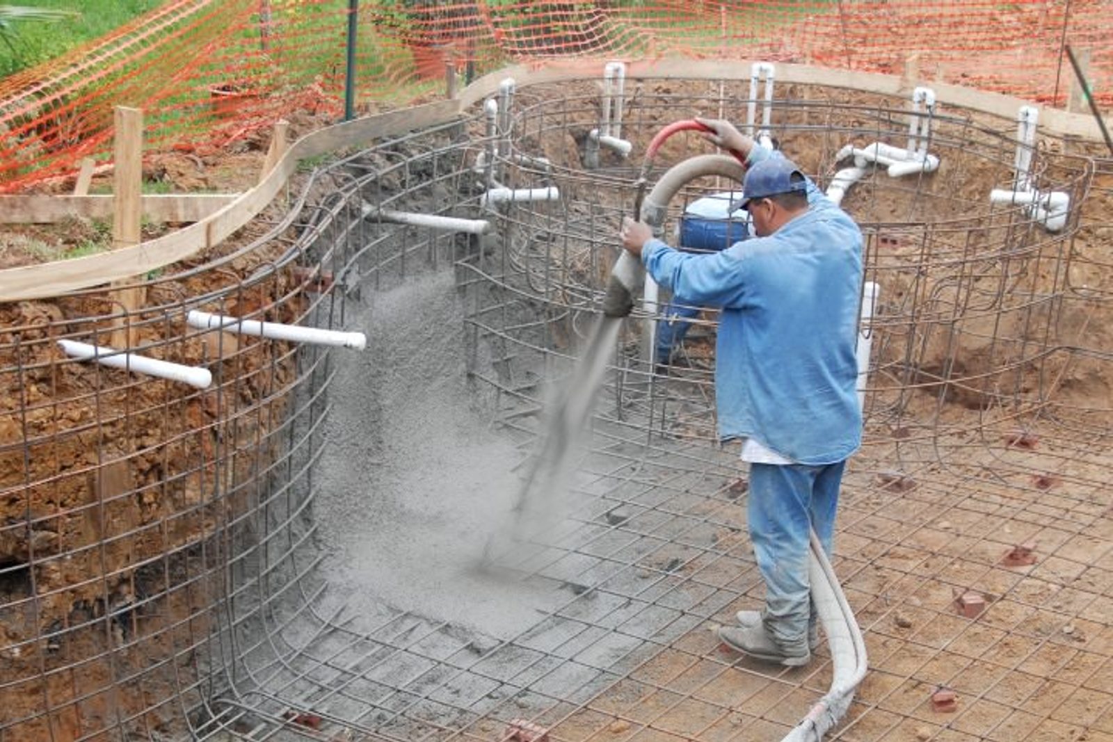Professional applying concrete to the pool shell, marking a key stage in the pool construction process