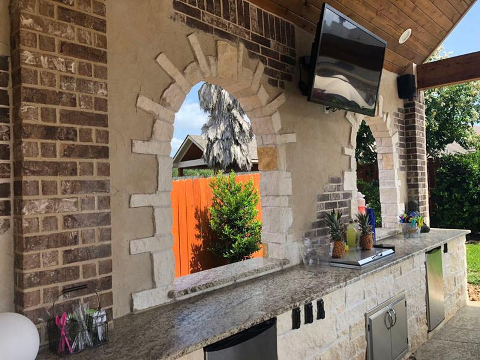 Houston backyard outdoor kitchen with stylish stone arches, beverage station, and granite countertop