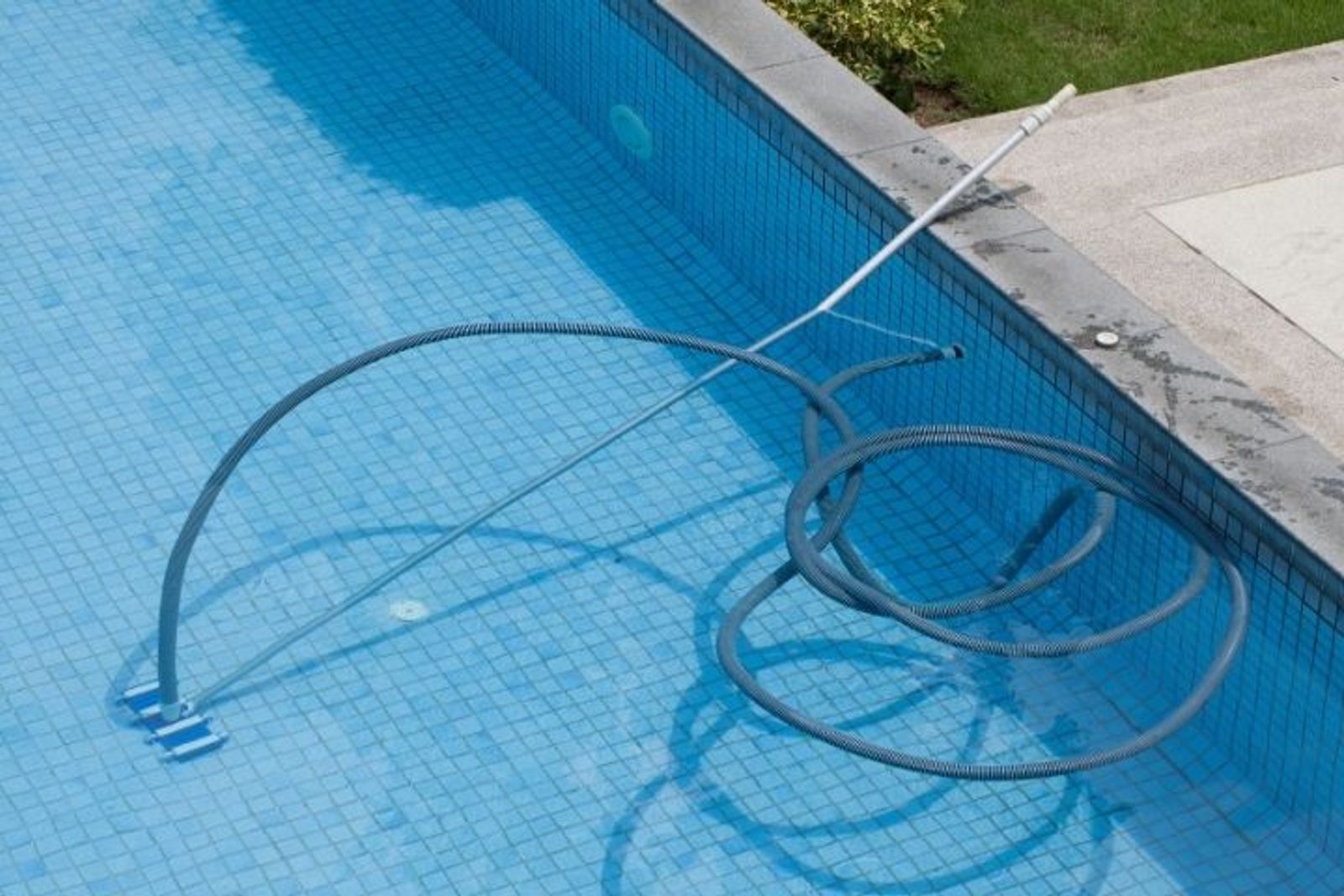Pool vacuum cleaning a tiled swimming pool interior during routine maintenance