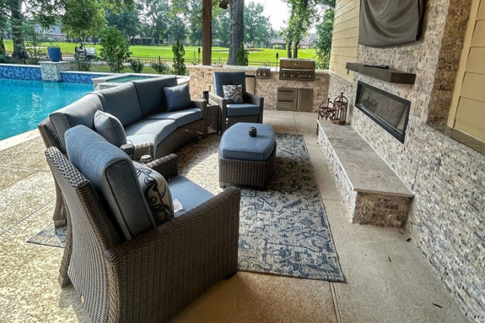 Outdoor living space featuring a custom kitchen, poolside seating, and a built-in grill