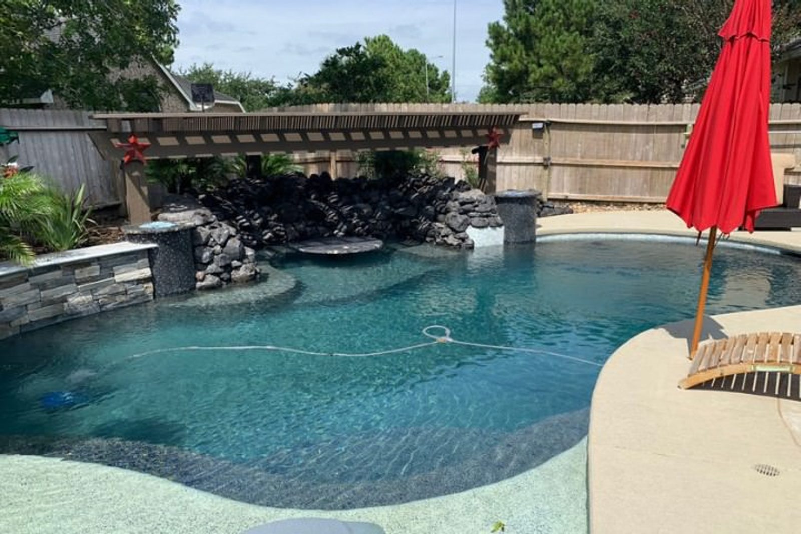 Custom pool in Houston featuring built-in loungers and a shaded grotto
