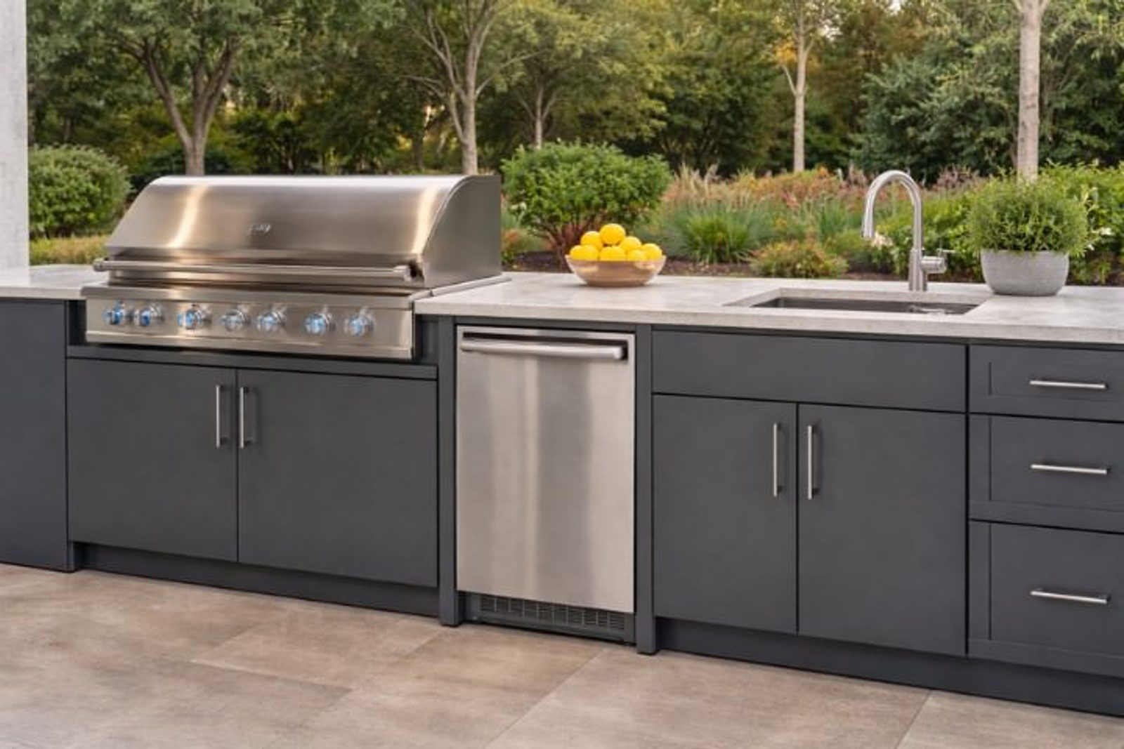 Modern outdoor kitchen with dark gray powder-coated metal cabinets, stainless grill, sink, and beverage fridge in a clean linear layout
