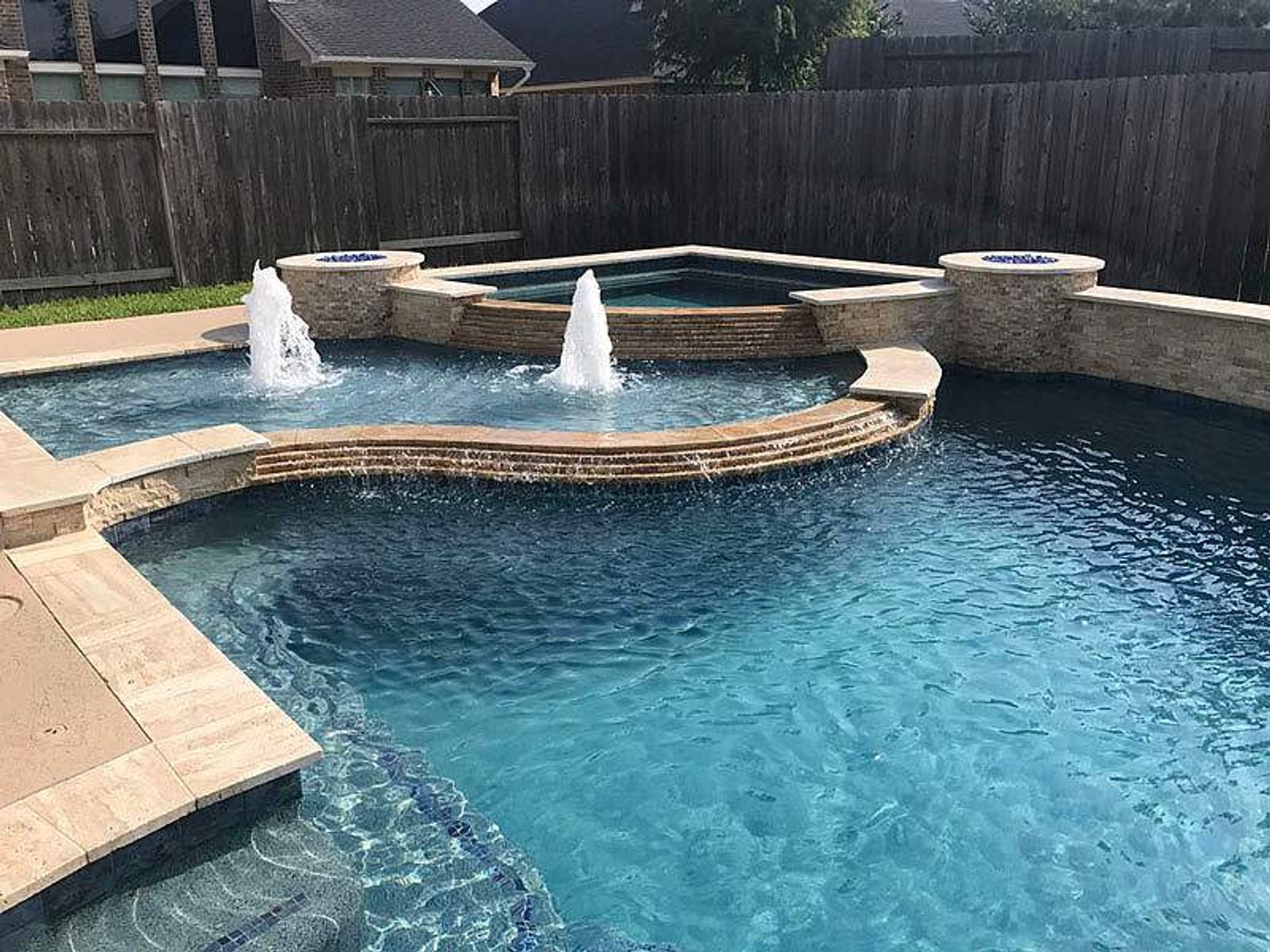 Custom-designed pool featuring an elevated spa and water features in Houston