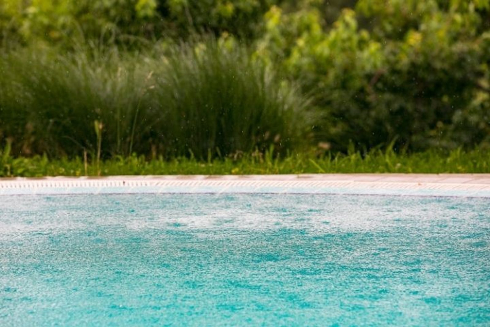 Rain falling on a Houston pool where weather can affect water balance and maintenance