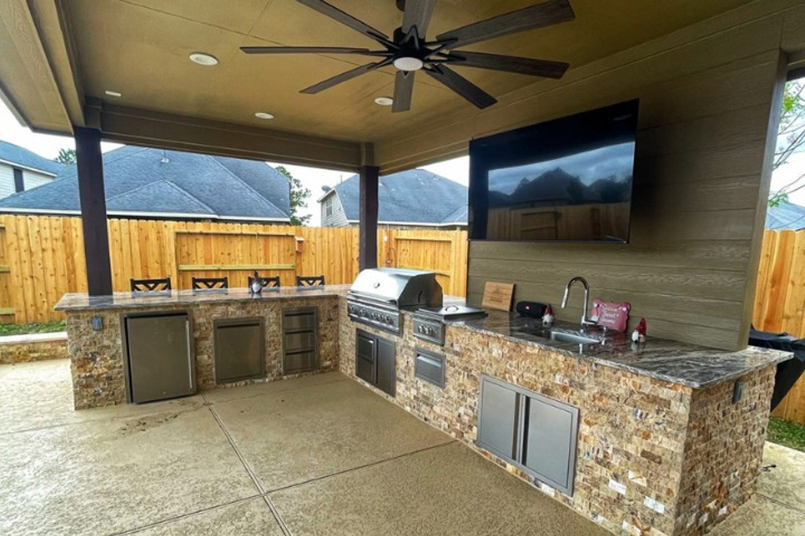 L-shaped outdoor kitchen with built-in grill and bar seating in a Houston backyard