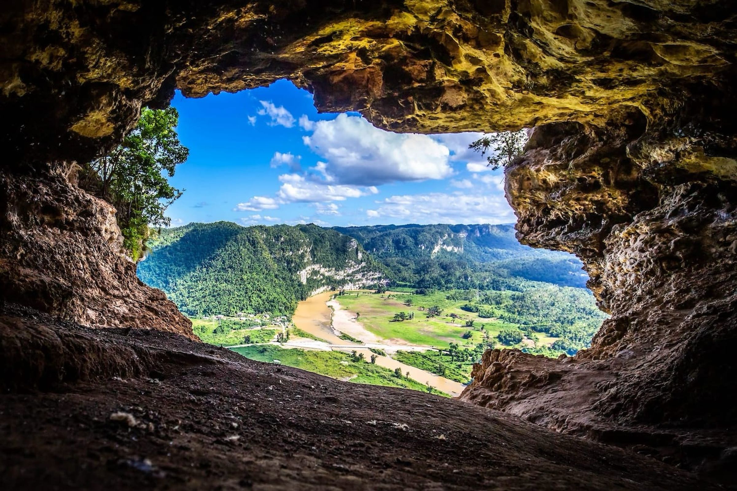 Lush green valley viewed from inside a cave opening