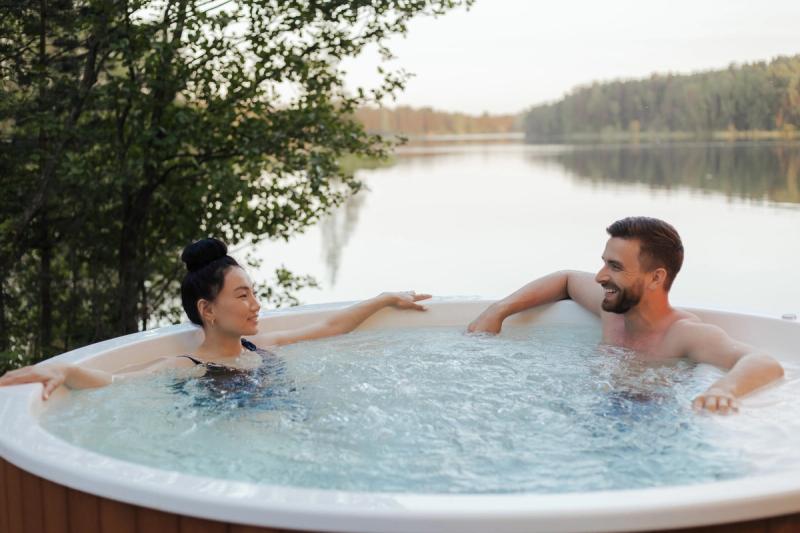Two people sitting in a hot tub overlooking a lake