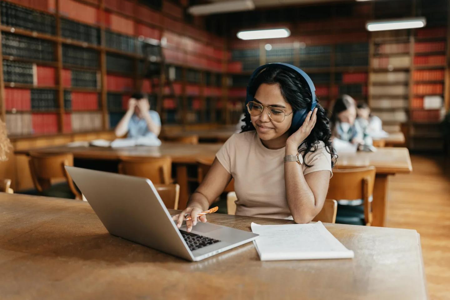 A student in headphones studying online in a university library.