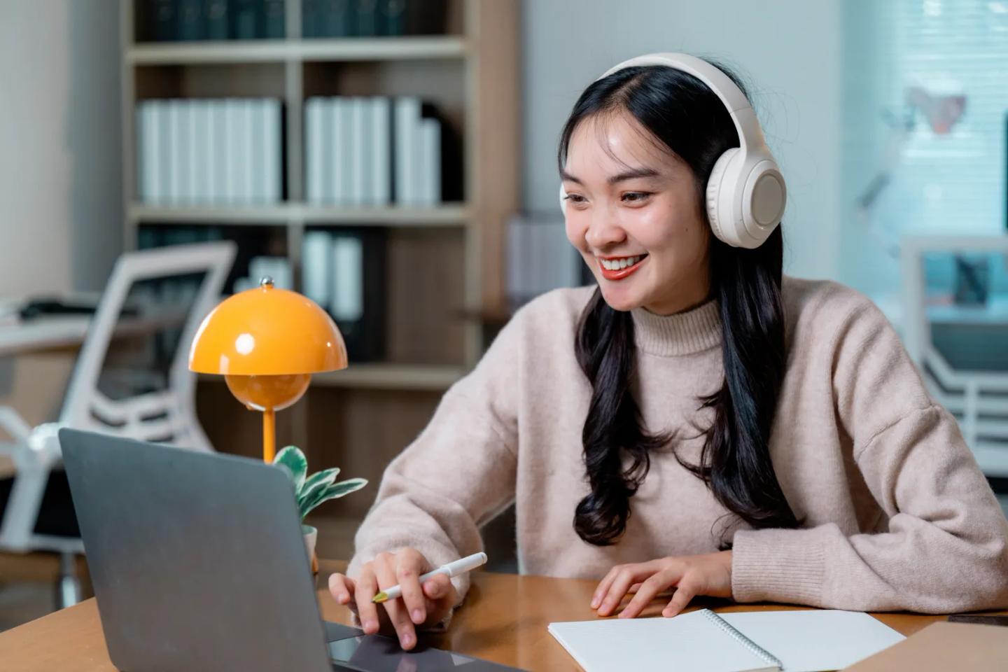 A learner in headphones attending an online class on her laptop.
