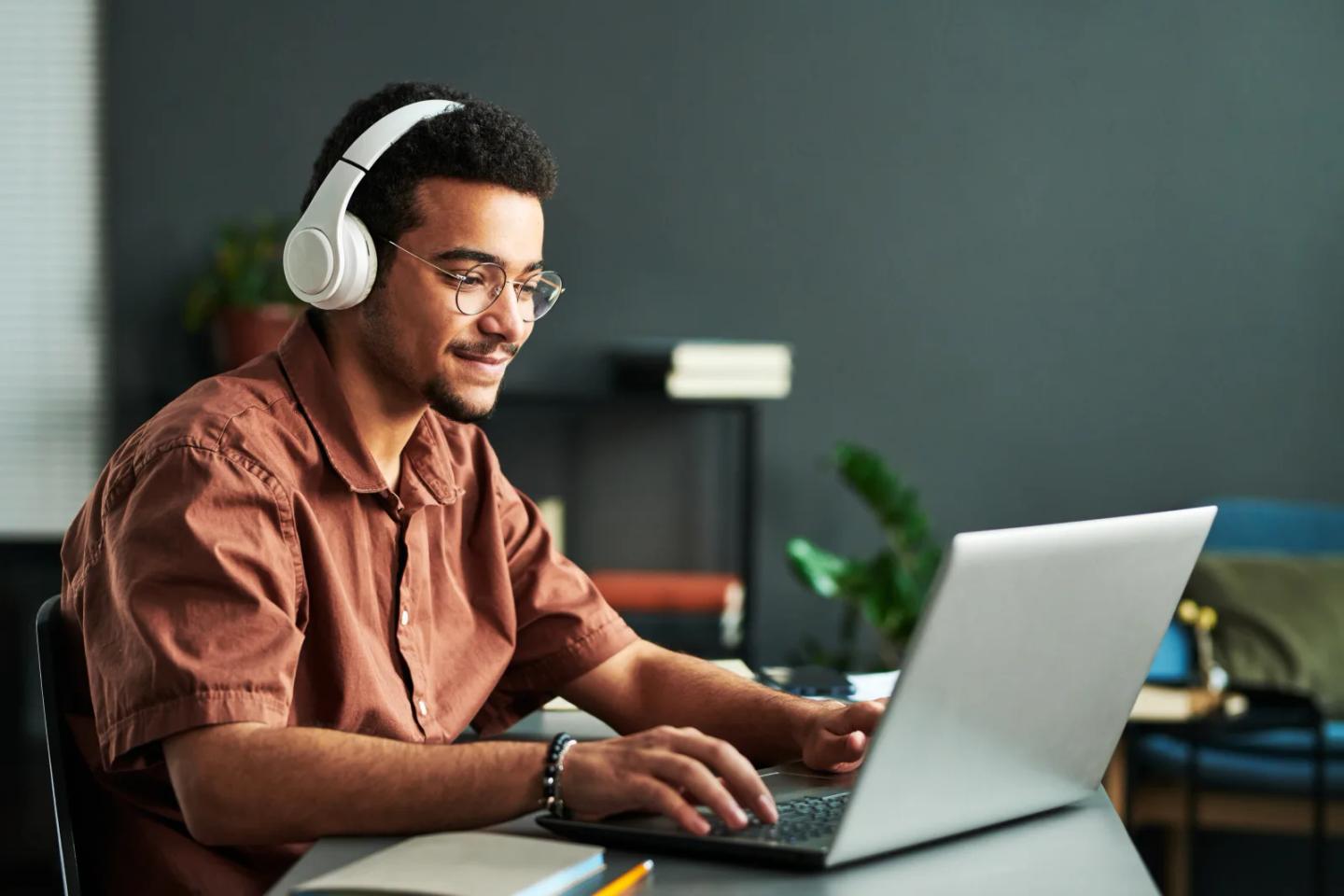 A learner in headphones working through coursework on a laptop.