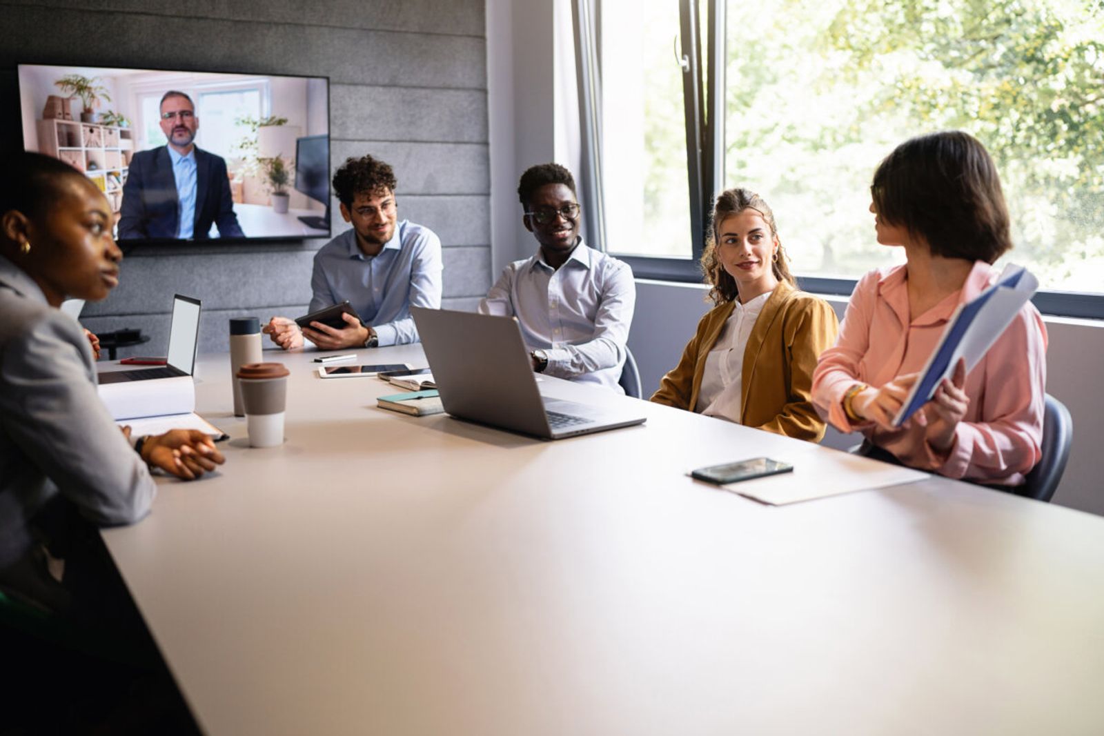 A multiracial group of young and senior business people having a video conference with a CEO at the meeting room