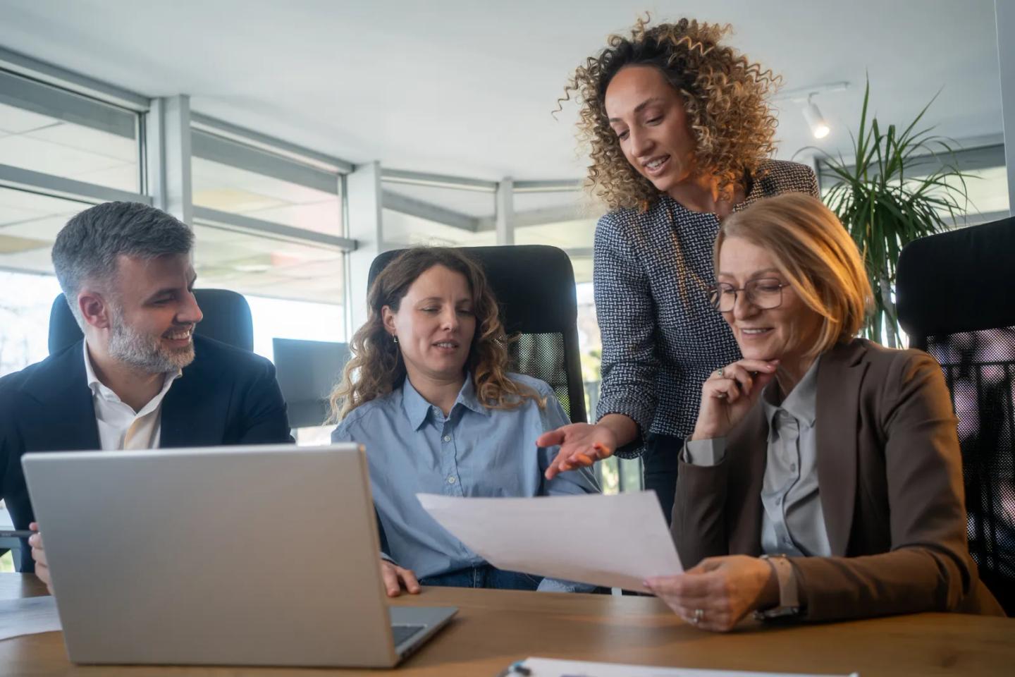 A university team reviewing a program proposal together at a laptop.