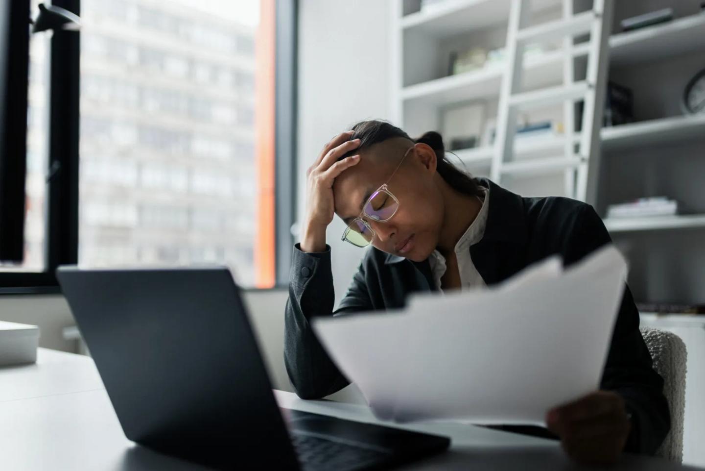 A program director reviewing paperwork at a laptop.