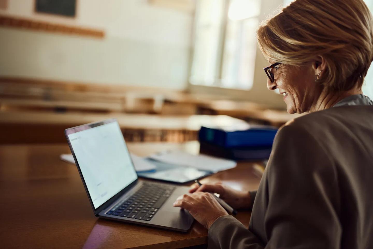 A faculty member reviewing curriculum on her laptop.