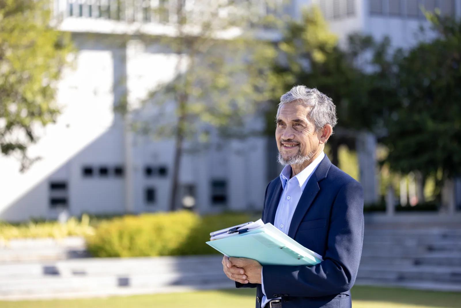 A program leader carrying accreditation files across campus.