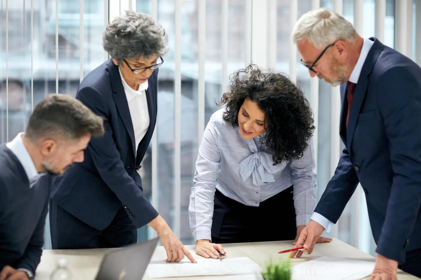 A team reviewing compliance plans around a table.
