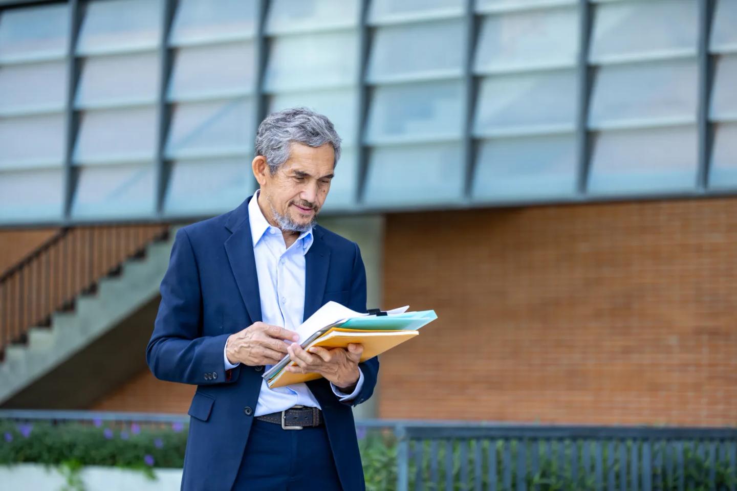 A program leader reviewing documents outside a campus building.
