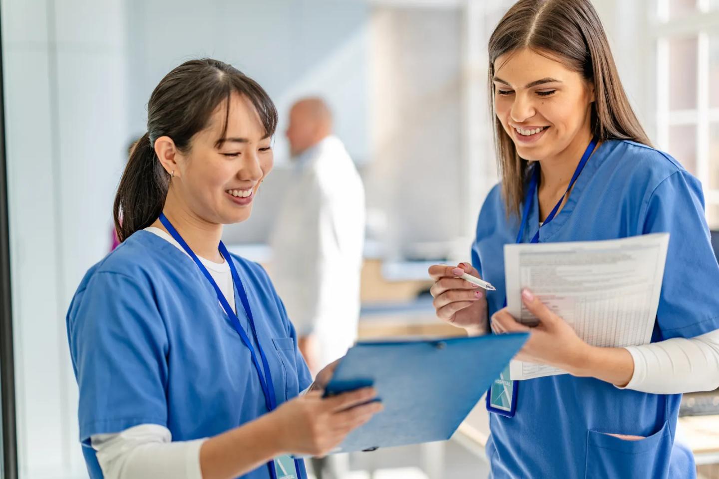 Two healthcare educators reviewing learner progress on a clipboard.