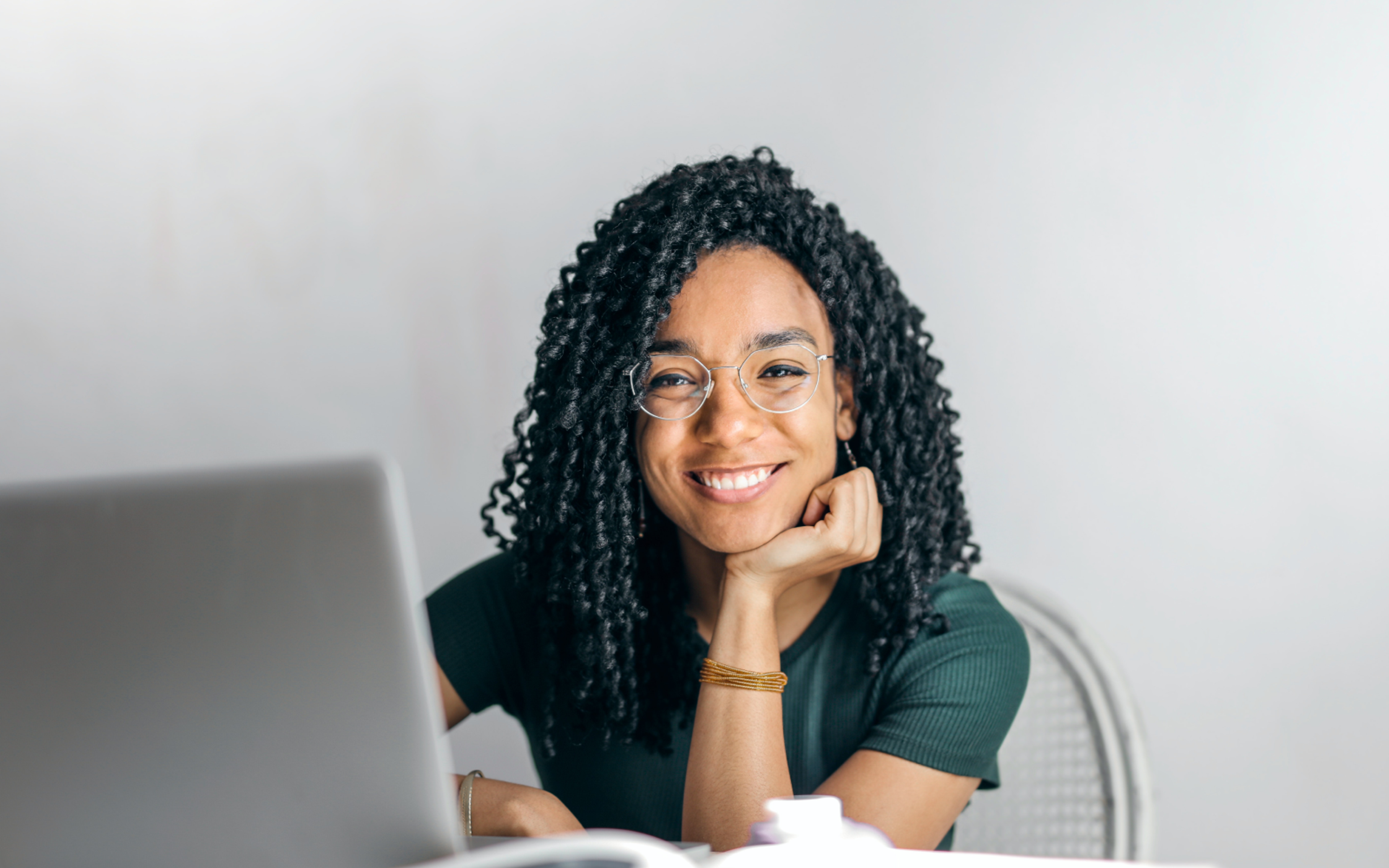 Happy woman sitting at table with laptop