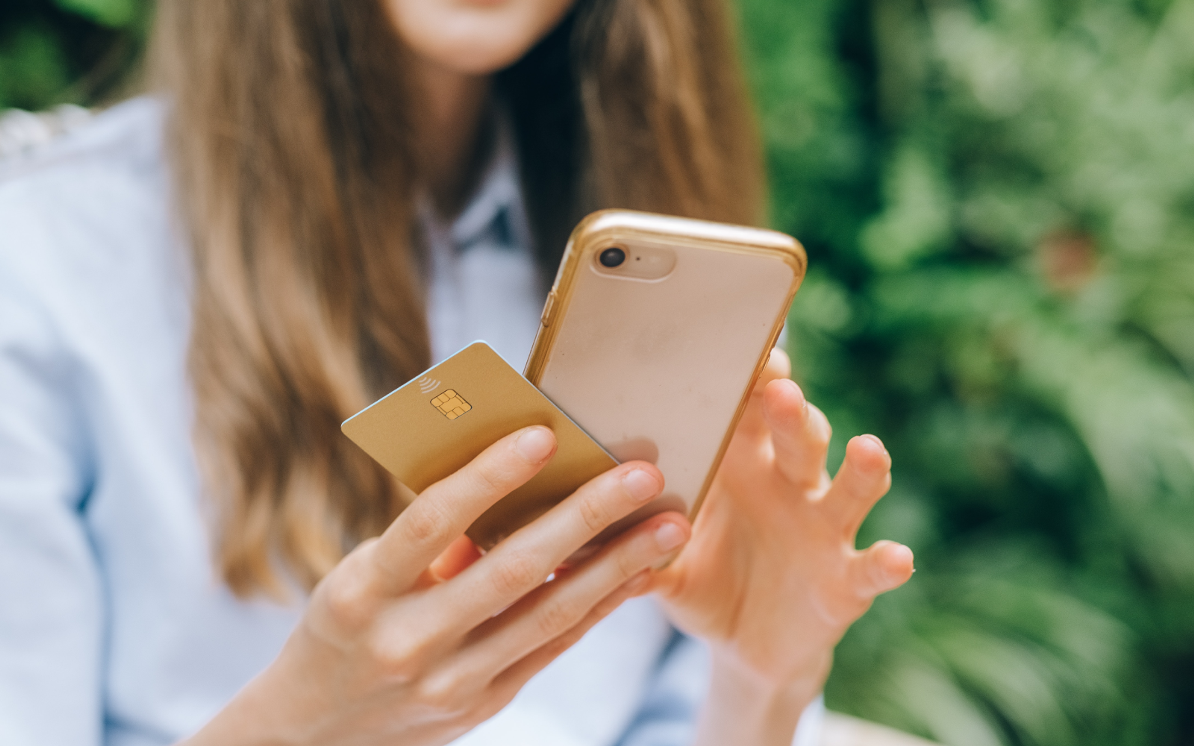 A Woman Using Her Smartphone while Holding a Credit Card
