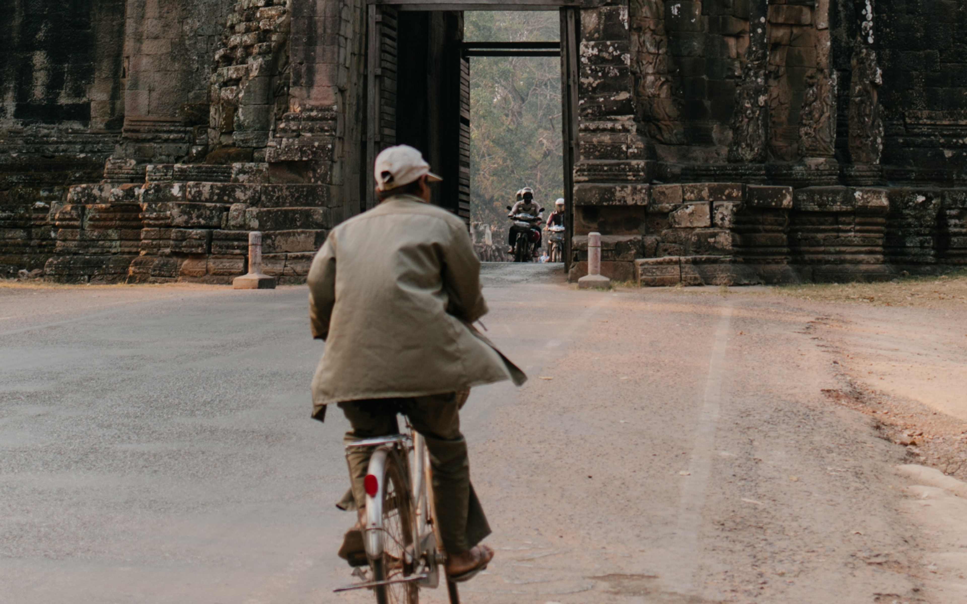 Woman in White Jacket Walking on Pathway Near Gray Concrete Building Cambodia
