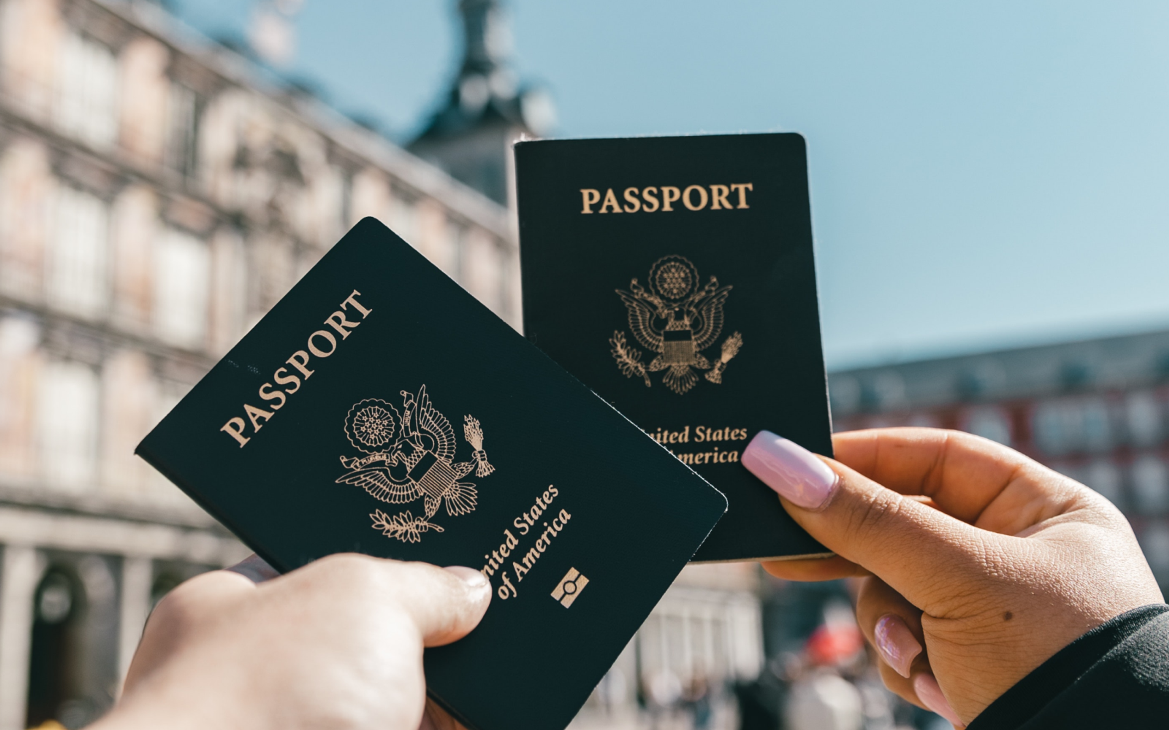 Anonymous tourists showing US passports on street on sunny day
