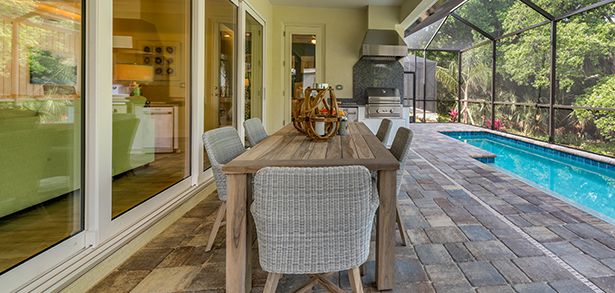 Covered lanai dining area beside screened pool in Sam Rodgers home