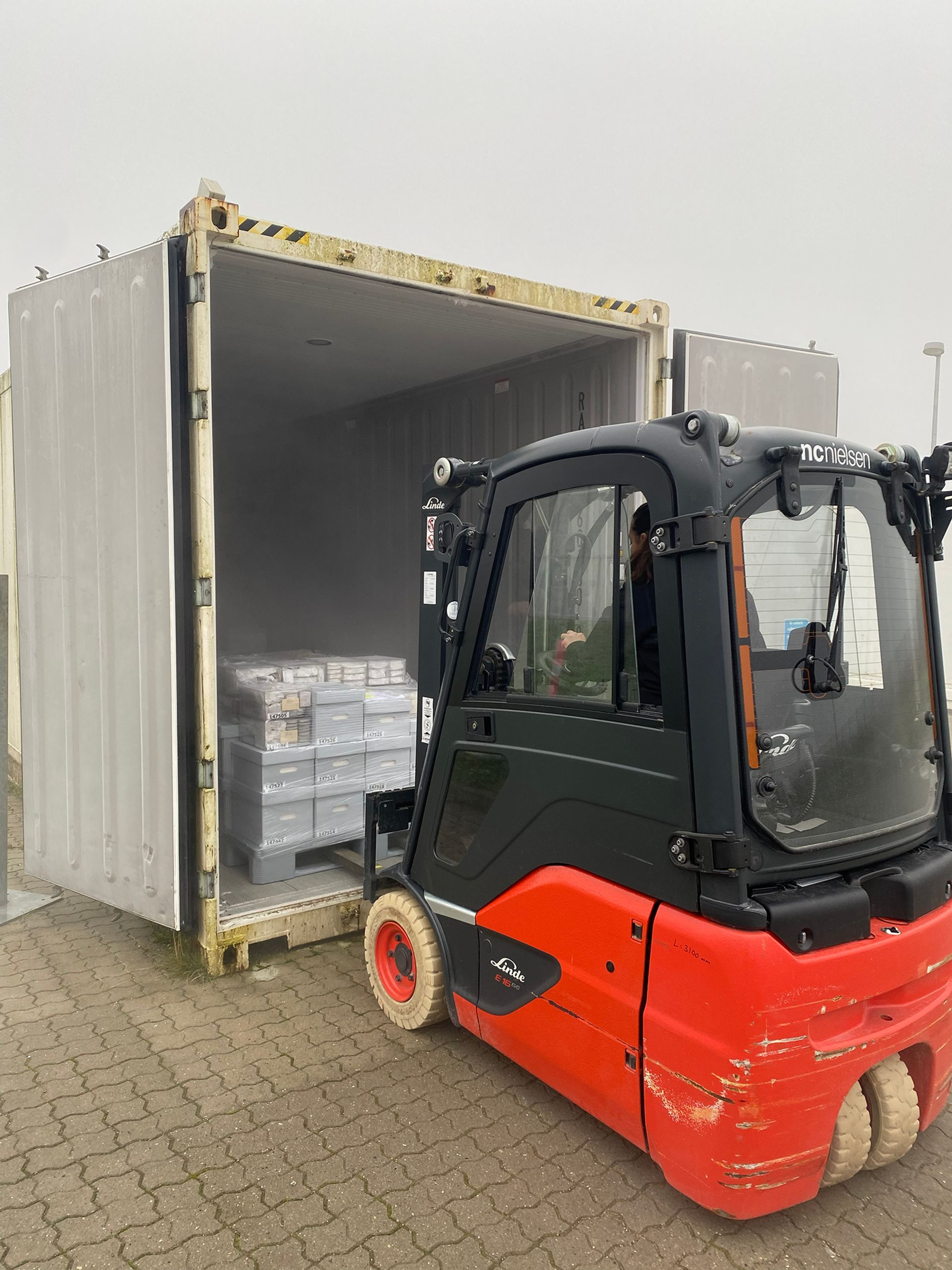 Aflæsning af en container med ting til magasinering med en gaffeltruck.