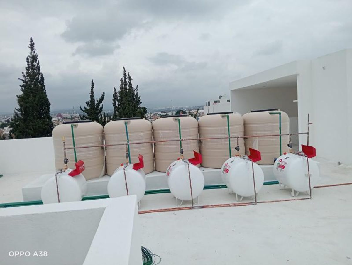 Azotea con cinco tinacos de agua beige y cinco tanques estacionarios de gas blancos