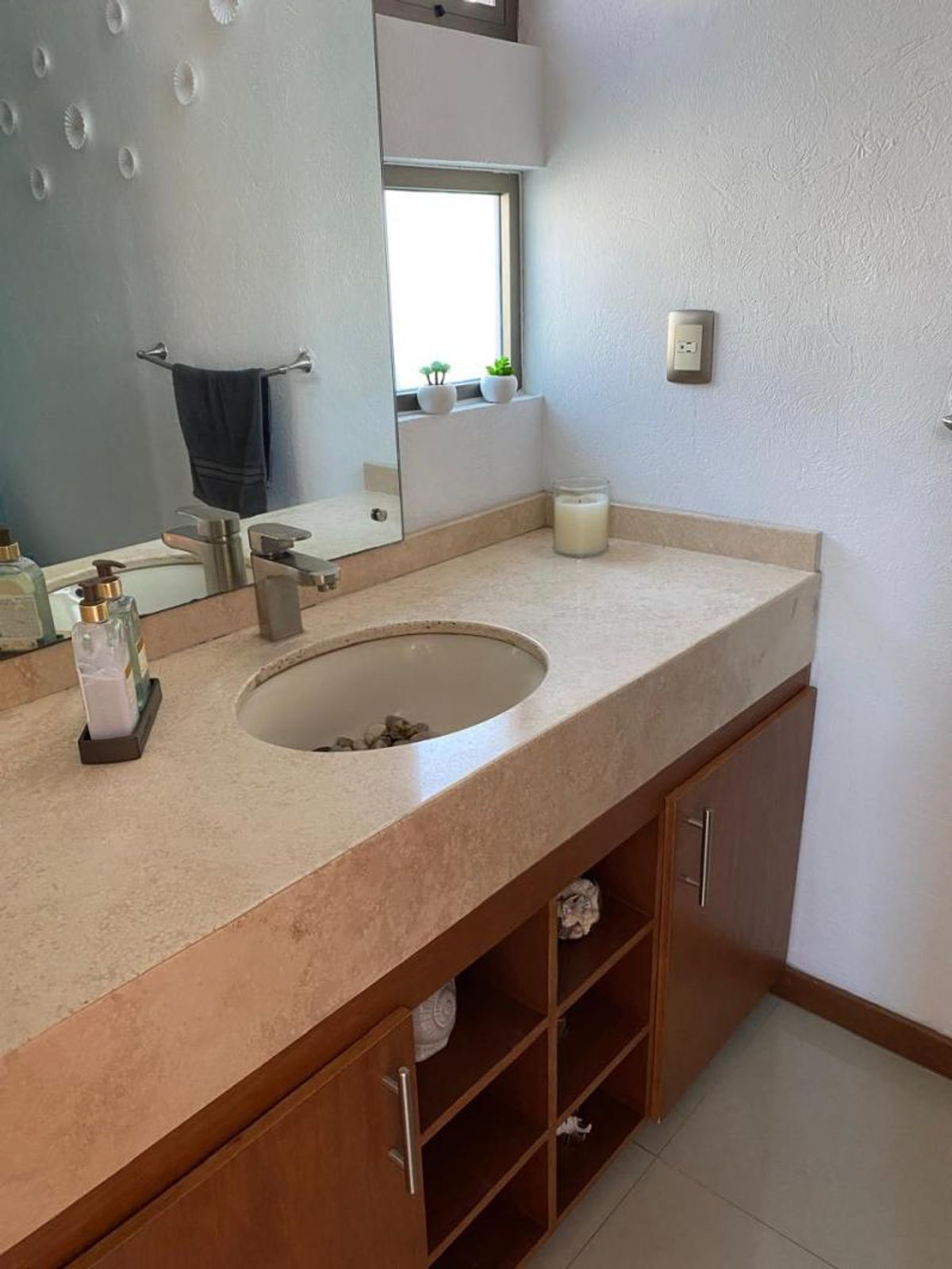 Mueble de baño de madera con cubierta beige, lavabo empotrado, grifo monomando y espejo