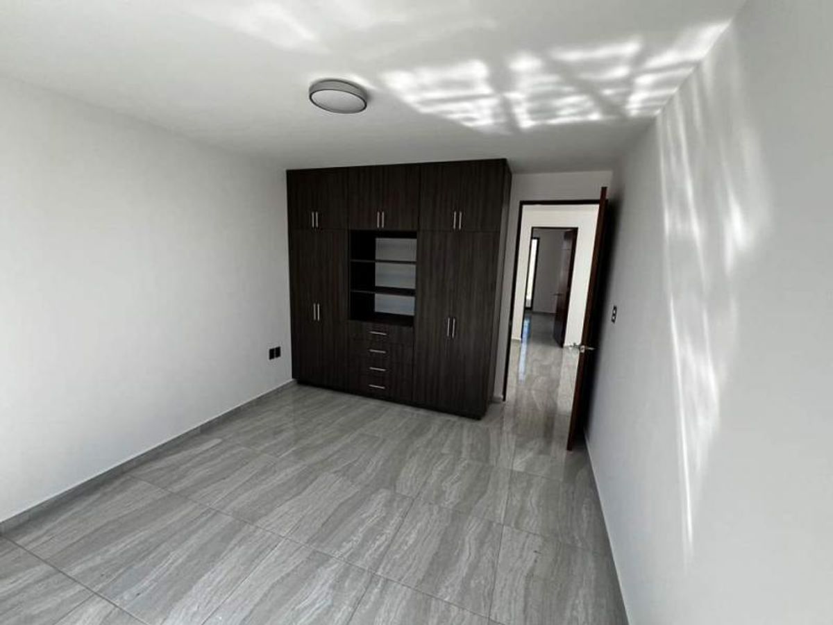 Recámara vacía con clóset de madera oscura, paredes blancas y piso cerámico gris