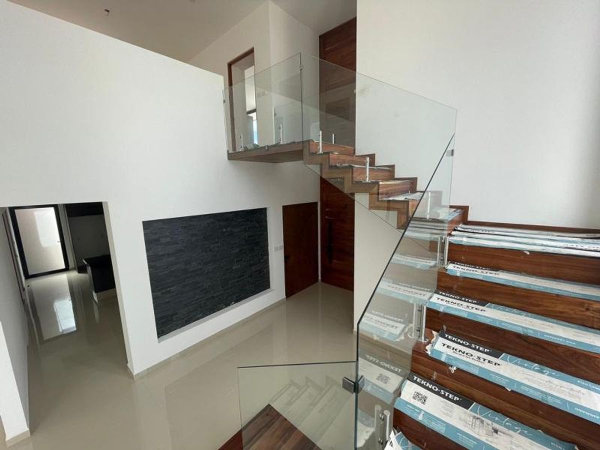 Escalera de madera con barandal de cristal junto a muro de piedra oscura