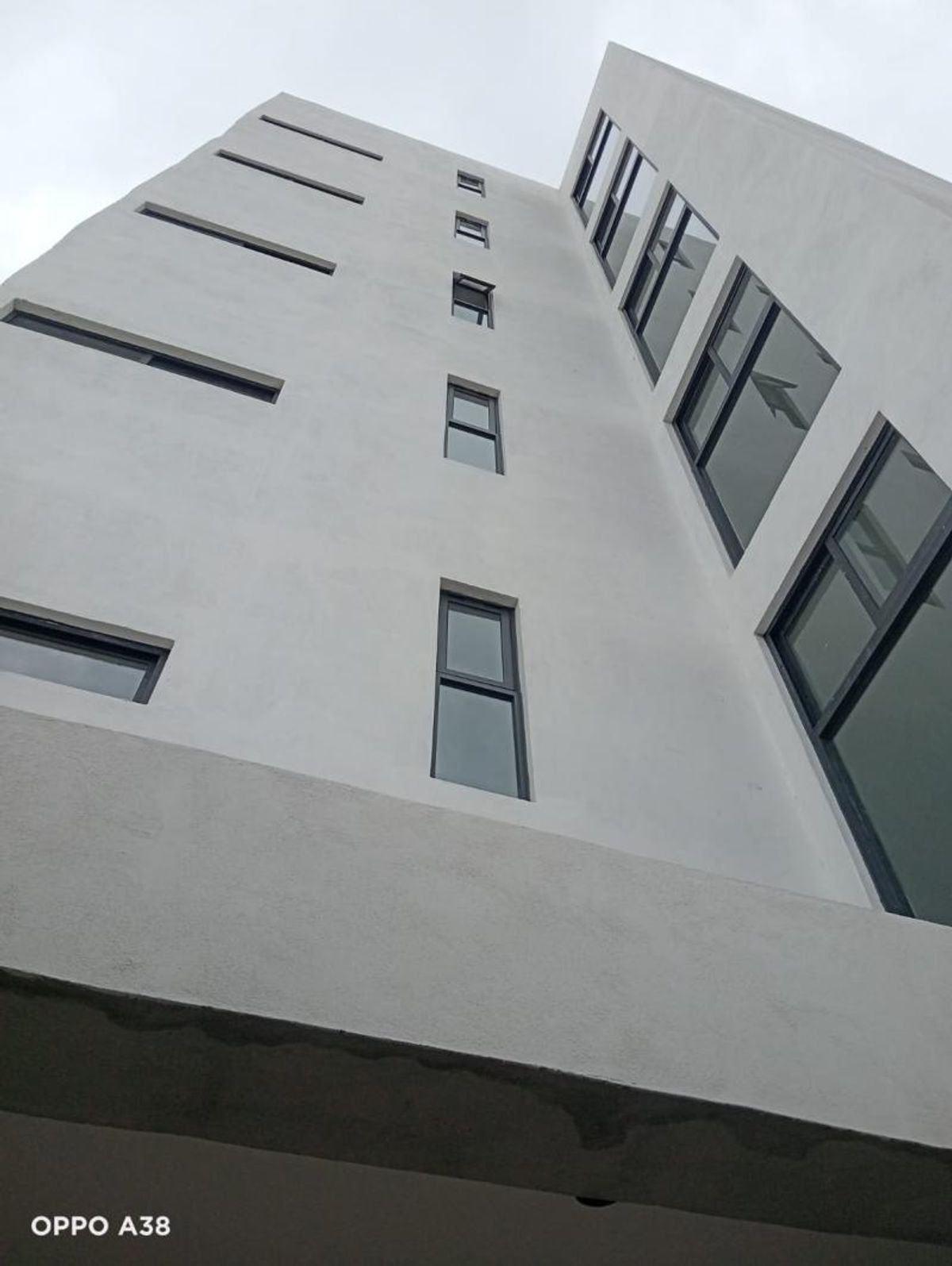 Fachada de edificio gris vista en contrapicado con ventanas rectangulares de marcos oscuros