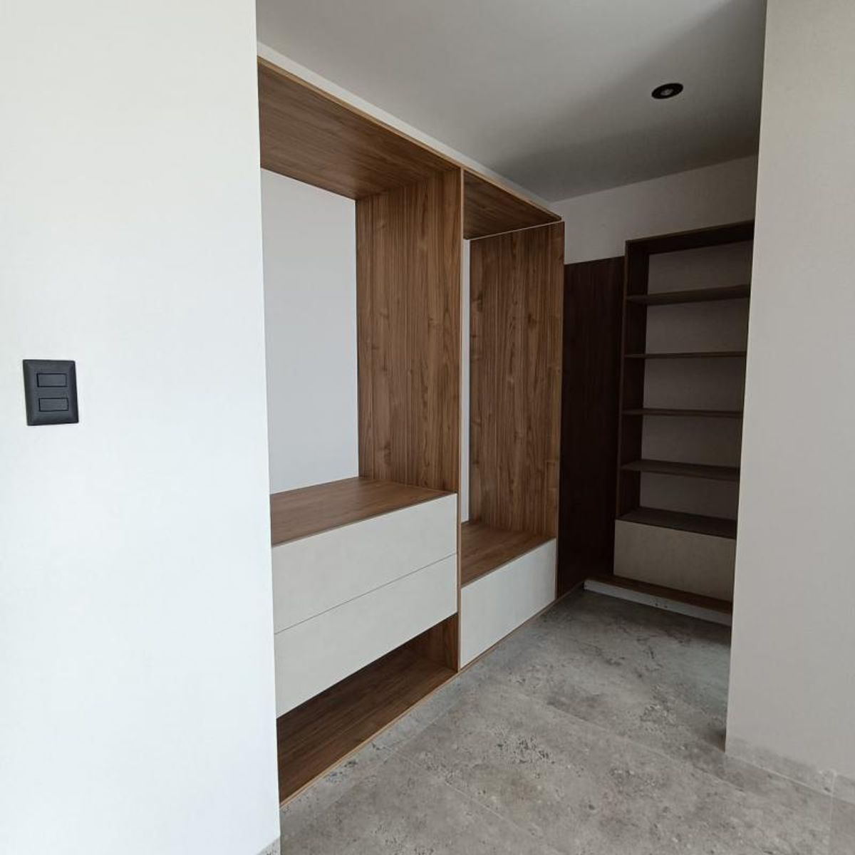 Vestidor de madera con cajones blancos, repisas abiertas y piso gris de porcelanato
