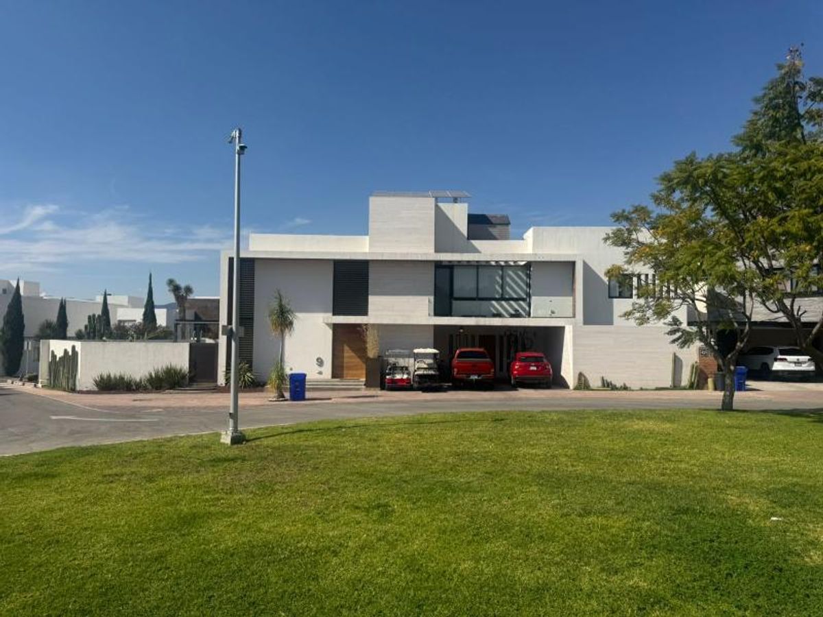 Fachada de casa moderna blanca de dos niveles con cochera y amplio jardín frontal